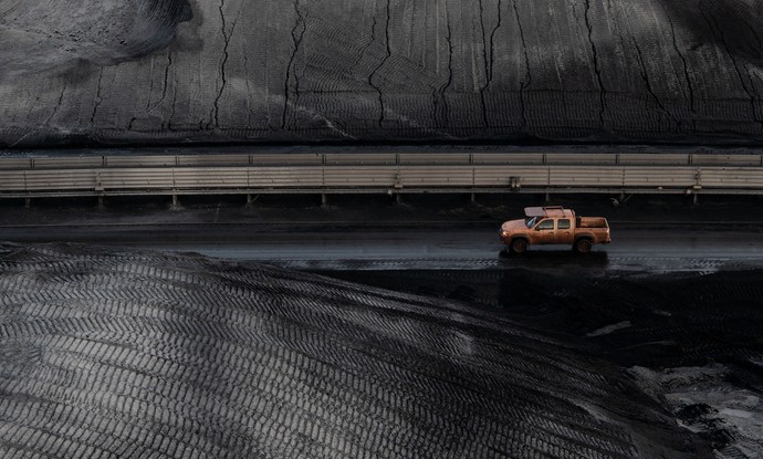 Ein roter LKW fährt durch eine Kohlelagerstätte.