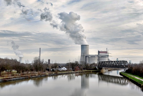 Ein Kanal mit Industriegebäuden und rauchenden Schornsteinen im Hintergrund