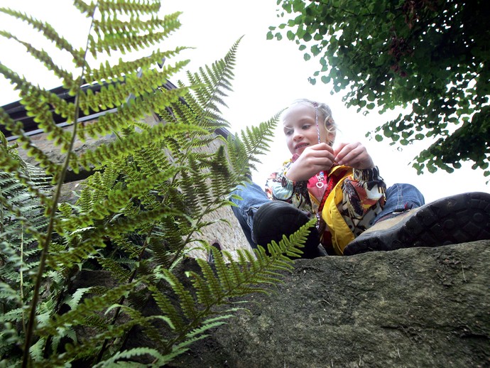 Mädchen im Schneidersitz zwischen grünen Pflanzen