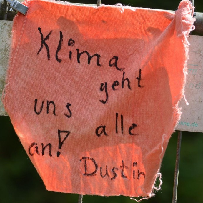 Rotes Stofftuch mit Aufschrift "Klima geht uns alle an" (vergrößerte Bildansicht wird geöffnet)