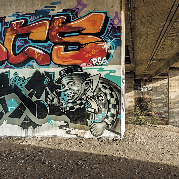 Ein Brückenpfeiler mit verschiedenen bunten Graffiti-Schriftzügen (vergrößerte Bildansicht wird geöffnet)