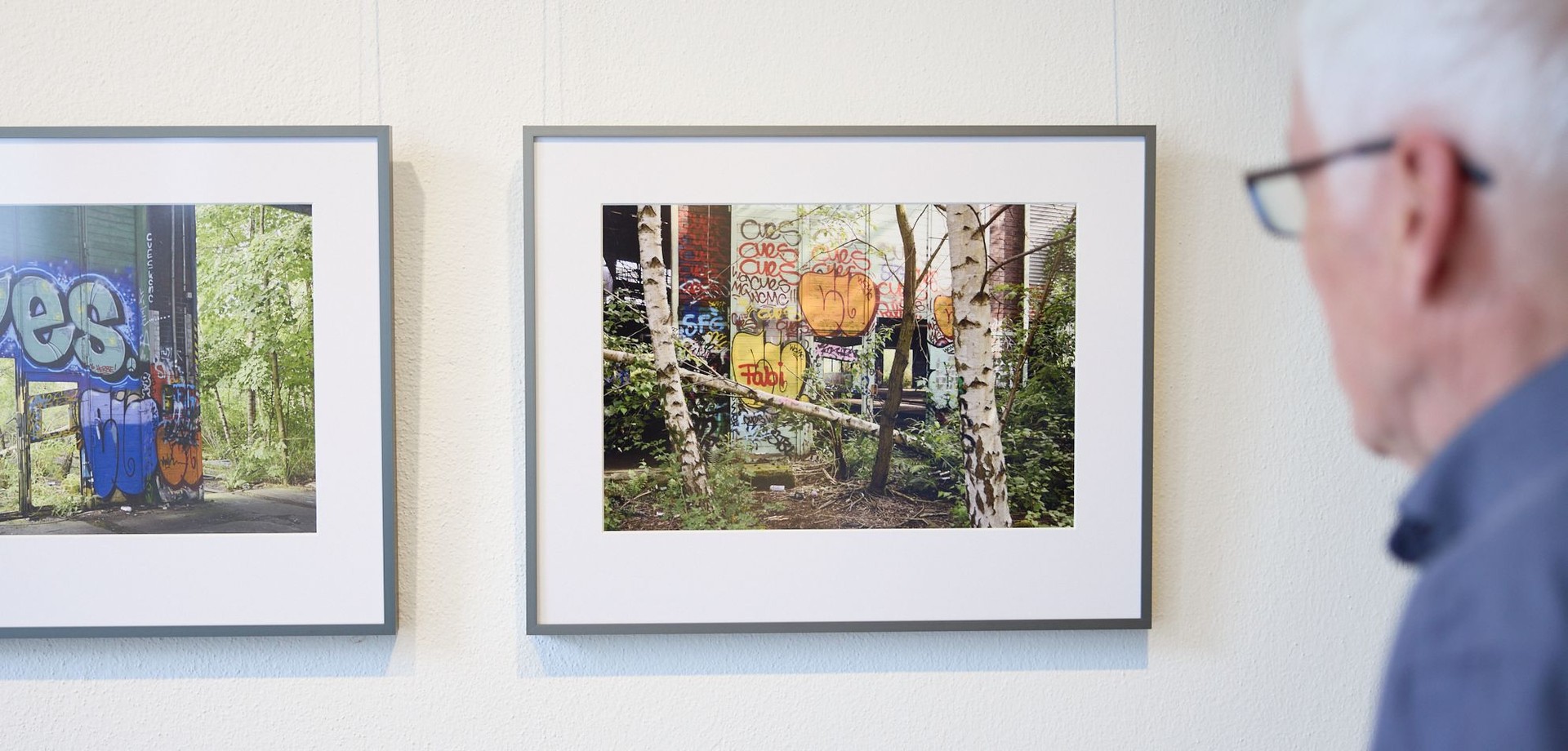 Jochaim Schumacher blickt auf zwei seiner Fotografien in der Ausstellung "Birke und Brache".