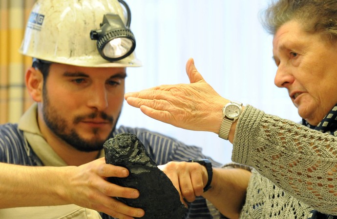 Museumspädagoge zeigt Seniorin ein Stück Kohle