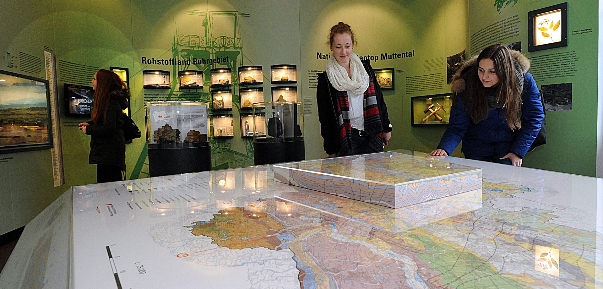 Besucherinnen in der Ausstellung des Informationszentrum GeoPark vor einer grioßen Landkarte,