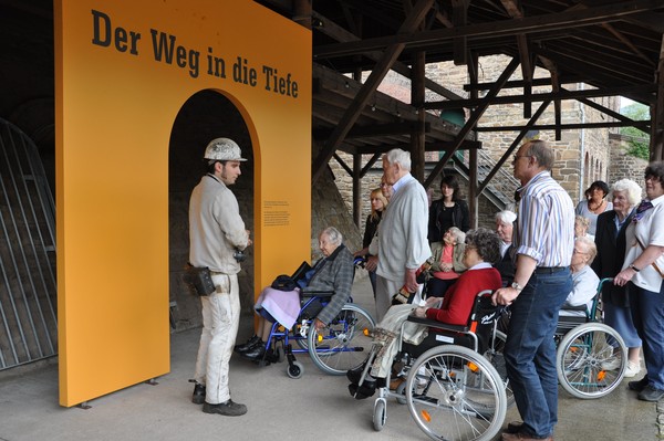 Führung mit Rollstuhlfahrerinnen vor der Ausstellung "Der Weg in die Tiefe"
