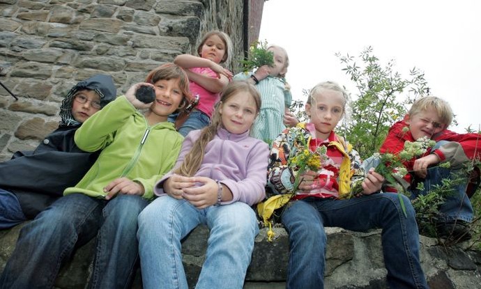 Gruppe von Kindern mit Pflanzen vor einem Zechengebäude